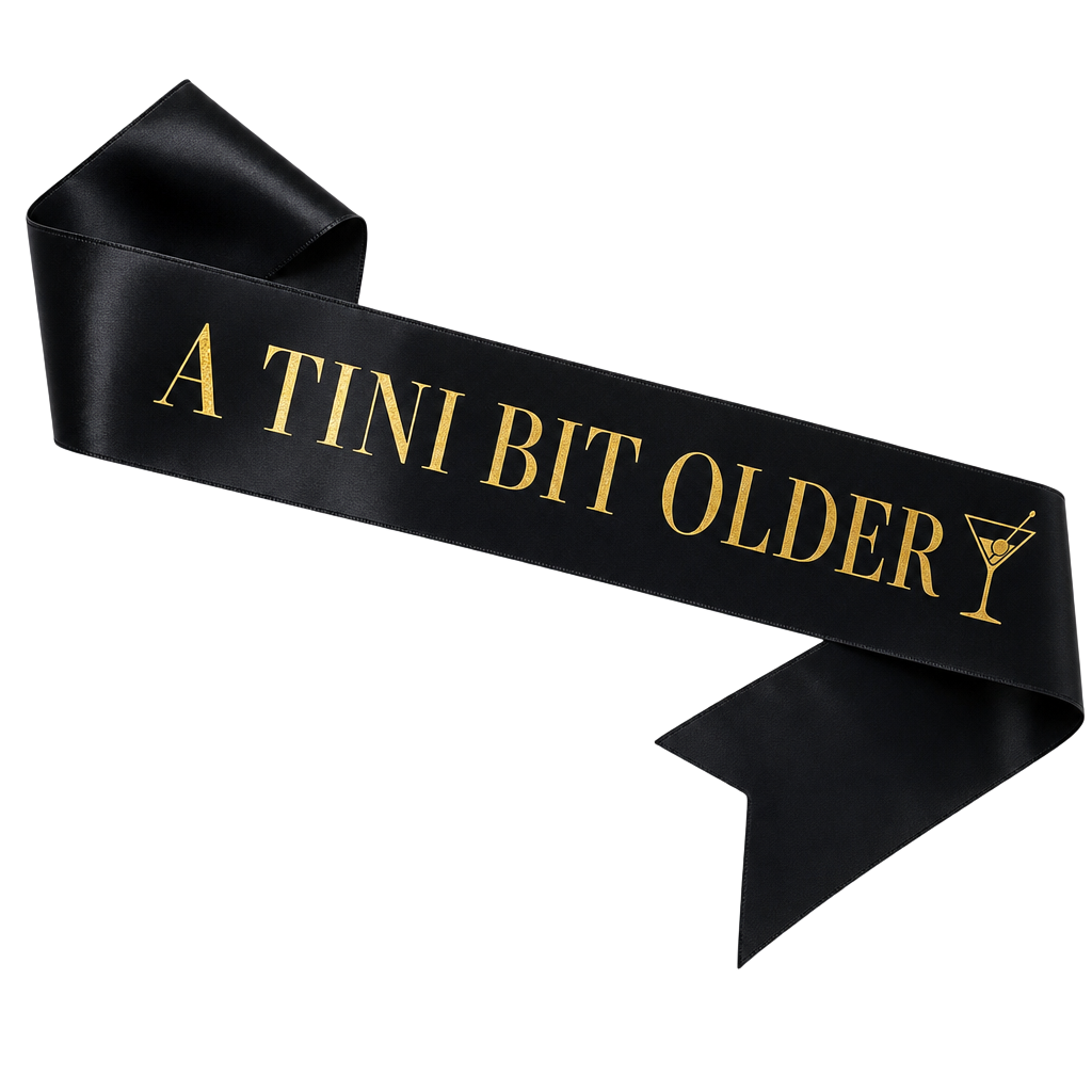 Black satin sash with gold foil lettering reading A Tini Bit Older
