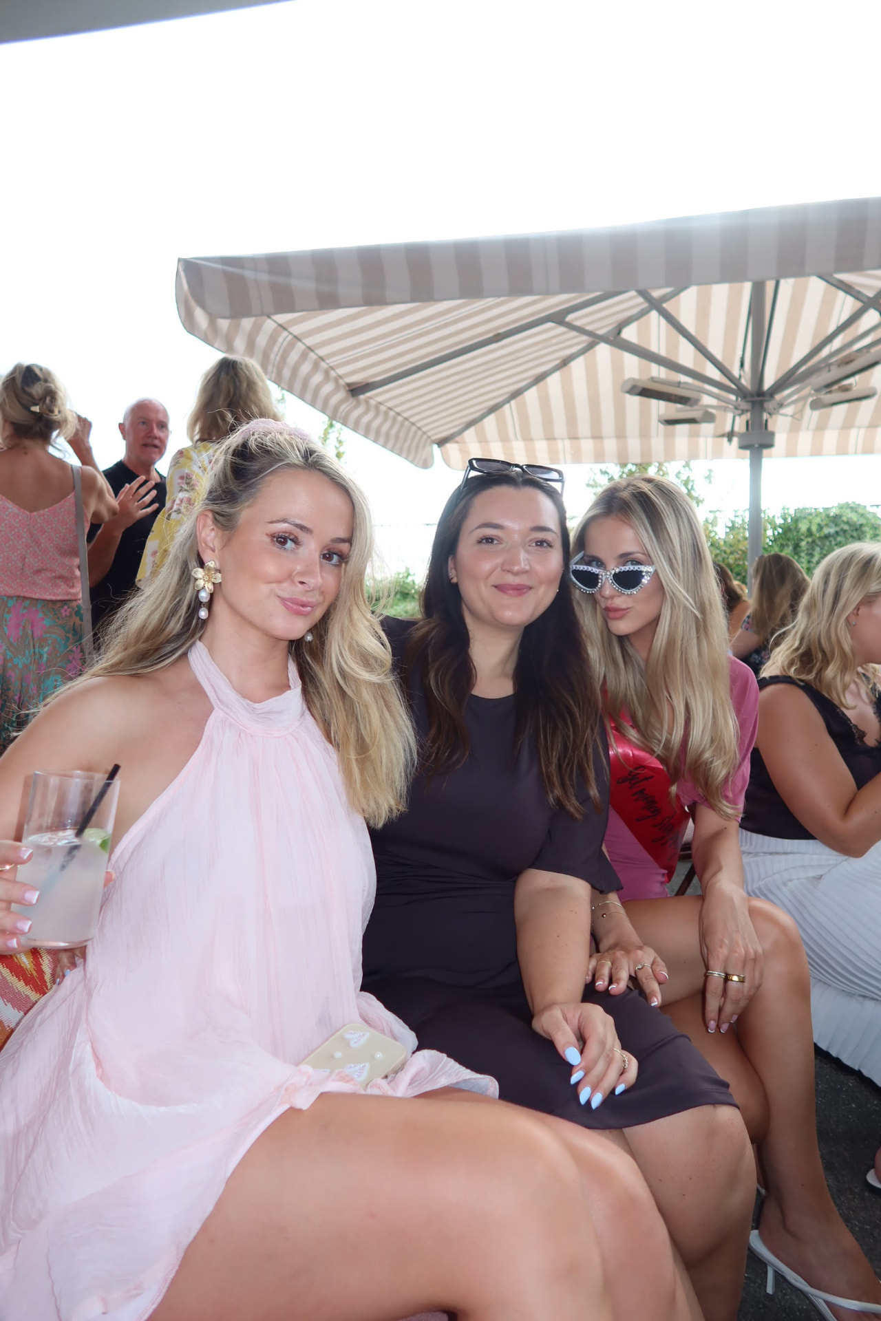 Guests on a striped-parasol terrace with cocktails