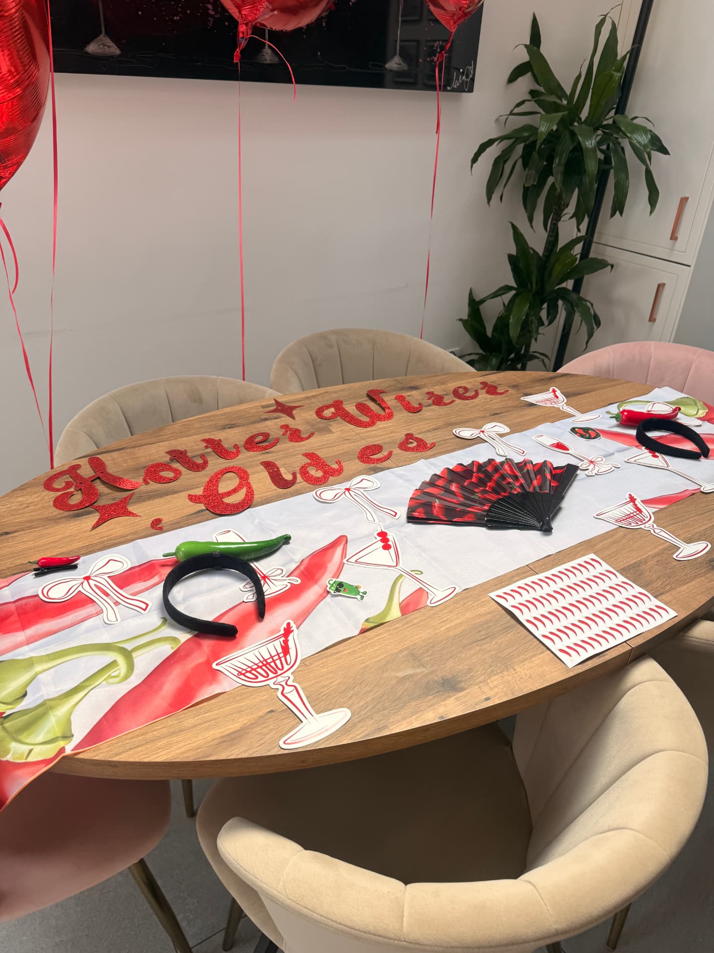 Table styled with red glitter Another Year Hotter lettering, chilli tablecloth, cocktail-glass place cards and heart balloons
